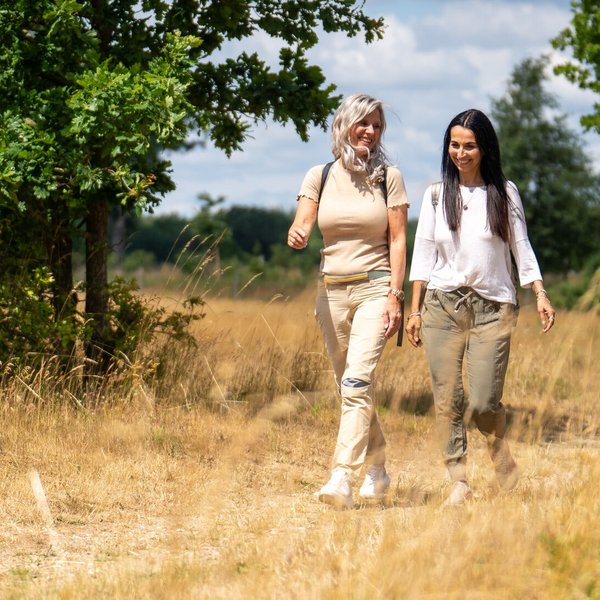 (© sh-tourismus.de/MOCANOX) Zwei Frau wandern durch eine idyllische Naturlandschaft in einem Naturpark.