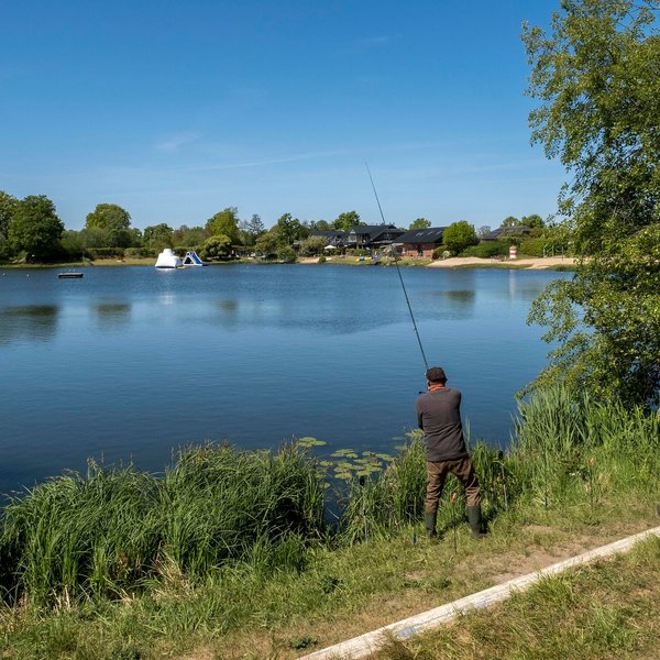 Ein Angler steht am See und angelt