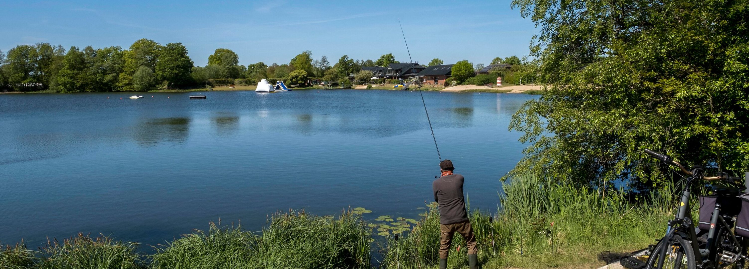 Ein Angler steht am See und angelt