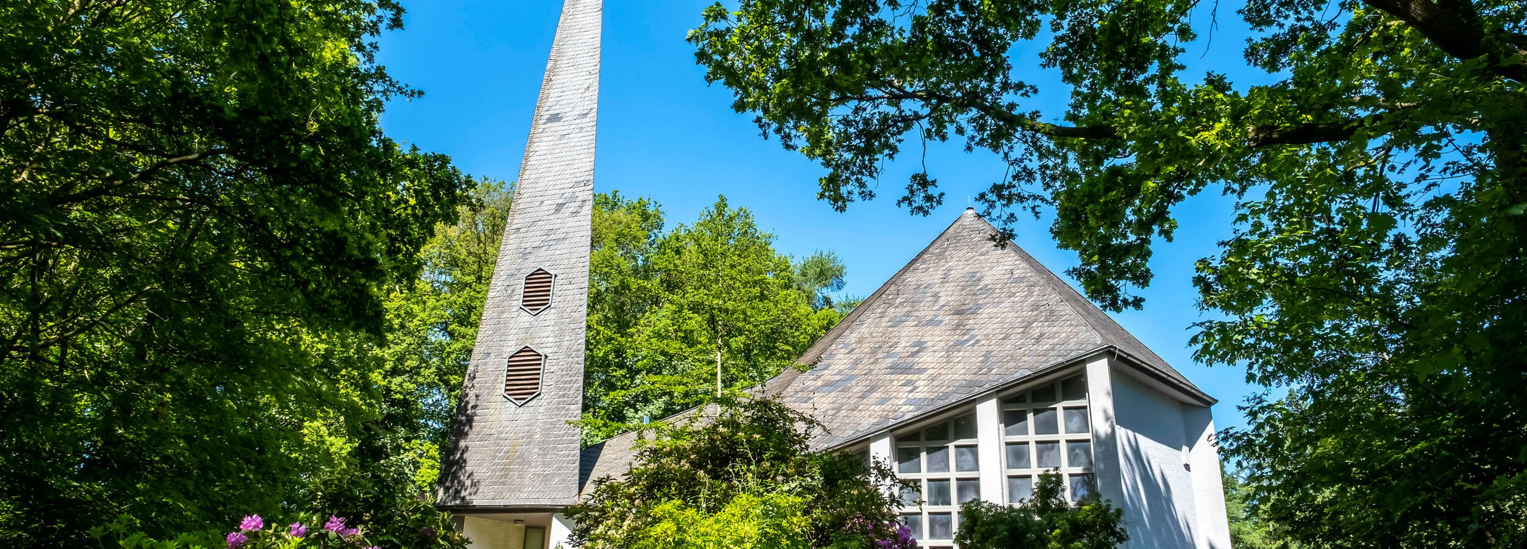 Weiße St. Johanneskirche unter grünen Bäumen in Gokels im Amt Mittelholstein