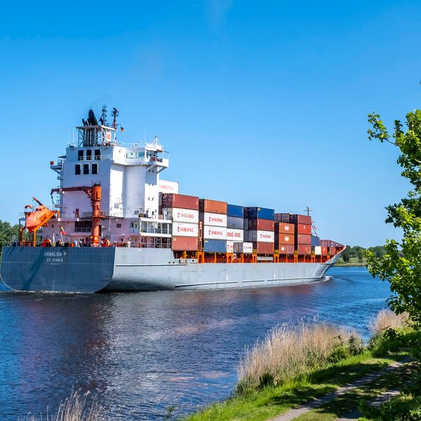 Ein Kontainerschiff fährt auf der Nord-Ostsee-Kanal an der Gemeinde Tackesdorf Amt Mittelholstein vorbei
