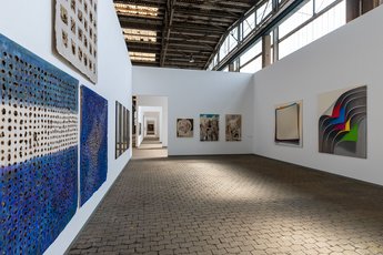 Eine Galerie voller Gemälde in einer historischen Halle.