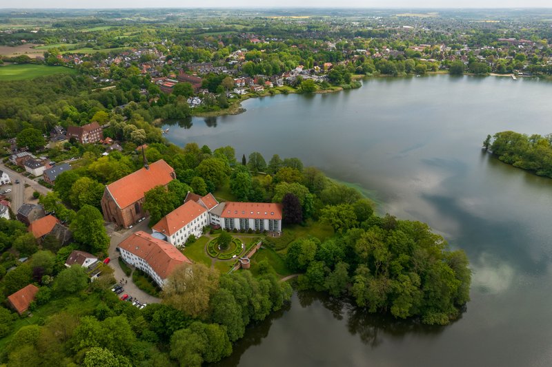 Luftaufnahme des Klosters Bordesholm am See mit umliegender Landschaft.