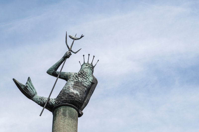Statue von Neptun mit Dreizack in Rendsburg vor blauem Himmel.